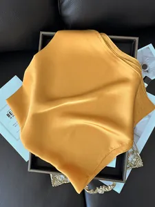 Gros plan du foulard en satin jaune gingembre avec texture en soie sur cuir noir