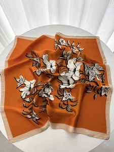 Close-up of silk square scarf featuring vintage orange floral patterns and cream borders