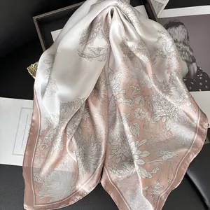 Detailed view of floral satin silk square scarf on premium black leather and magazine