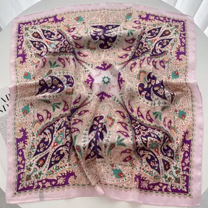 Detail of pink silk square scarf with colorful vintage paisley patterns on white surface