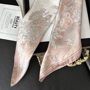 Detailed texture of pink silk scarf with floral patterns on black leather and gold tray