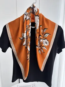 Detail of vibrant orange silk scarf with elegant black and white floral pattern
