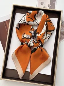 Detailed view of an orange silk floral scarf tied in a knot on a decorative tray