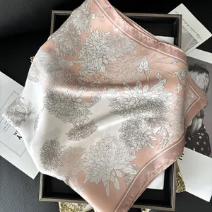 Pink and white silk square scarf with delicate chrysanthemum patterns on a dark tray
