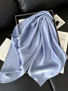 Gros plan du foulard en satin bleu clair montrant une texture lisse et un éclat soyeux
