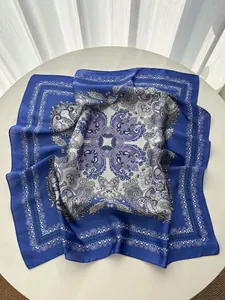 Macro detail of royal blue paisley silk scarf with bohemian patterns on white table