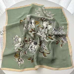 Close-up of floral silk scarf with elegant white magnolia prints on a sage green fabric
