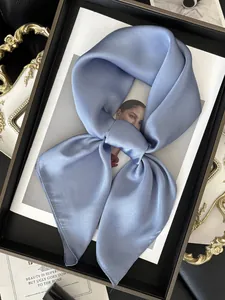 Détail d'un foulard en satin bleu clair noué montrant sa texture lisse et soyeuse