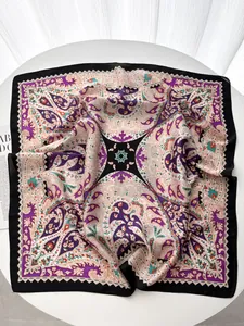 Detail of premium satin scarf with purple paisley print and elegant wavy edges on a table