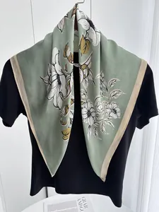 Detail of mint green floral silk scarf draped over a black shirt showing texture