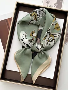 Detail view of bean green silk scarf with magnolia floral print in premium gift box