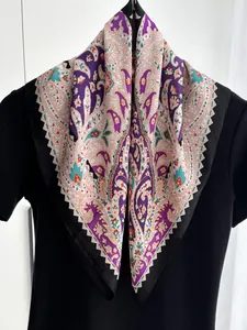Detail of faux silk square scarf featuring purple paisley patterns and satin texture
