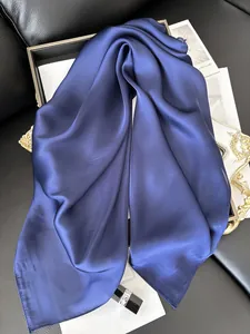 Détail d'un foulard en satin bleu foncé avec texture soyeuse sur cuir noir