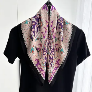 Close-up of printed silk-like square scarf with purple paisley patterns on a black shirt