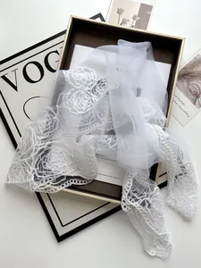 Detailed close-up of white bridal lace scarf with 3D rose embroidery and floral edges