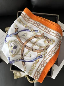 Detail of silk-like square scarf featuring golden chain and orange belt prints