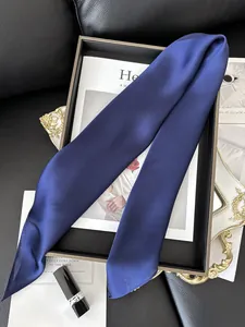 Vue détaillée d'un foulard étroit en satin bleu foncé drapé sur un cadre avec des accessoires