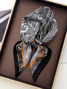 Detail of silk-like square scarf with black and white paisley pattern and orange borders