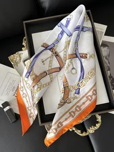 Detail view of satin scarf with horse chain print and orange border on leather background