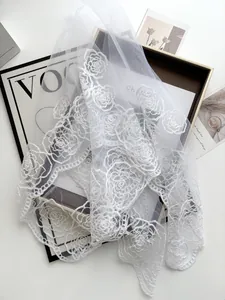 Close-up of white bridal lace veil with camellia embroidery and scalloped edges