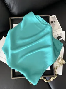 Détail d'un foulard carré en satin bleu sarcelle avec texture soie et ourlet roulé