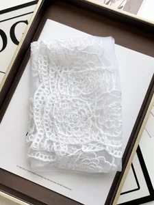 Detailed close-up of white floral lace shawl with camellia rose embroidery and mesh