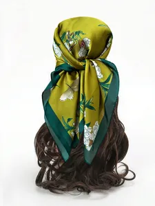 Detail of olive green silk scarf worn as a headscarf featuring floral and butterfly prints