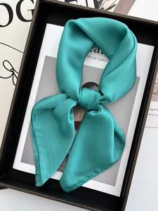 Gros plan d'un foulard carré en satin bleu sarcelle noué avec un éclat de soie chic