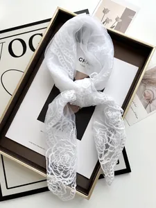 Close-up of white lace bridal scarf with delicate camellia rose embroidery on tray