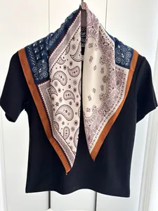 Detail of paisley silk scarf in blue and tan draped on a wooden hanger with black shirt