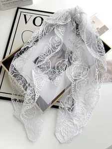 Close-up of elegant white fishnet lace bridal veil with delicate camellia rose embroidery