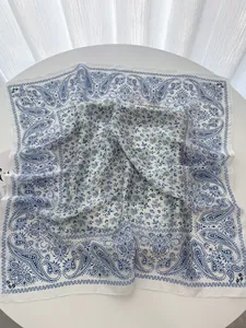 Close-up of luxury white silk square scarf with blue paisley and green floral patterns