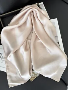 Vue détaillée du foulard carré en satin champagne avec texture soyeuse et reflets