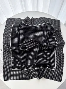 Close-up of elegant black silk square scarf with white polka dots and stitched borders
