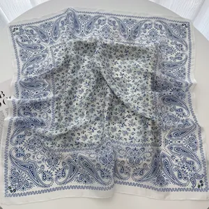 Detail of blue floral paisley pattern on white luxury square silk scarf with soft drape