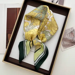 Détail d'un foulard en soie jaune avec imprimé floral dans un coffret cadeau