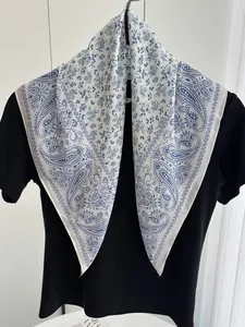 Detailed close-up of floral and paisley patterns on a white faux silk scarf for women