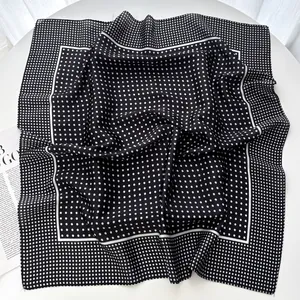 Detail of elegant black polka dot silk scarf showing smooth texture and draped fabric