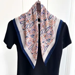 Detail eines Vintage-Seidenschals mit Paisleymuster und dunkelblauem Rand auf schwarzem Shirt