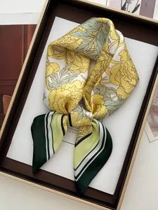 Détail d'un foulard en soie à fleurs jaunes et rayures vertes en boîte cadeau