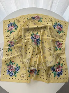 Detailed view of yellow paisley scarf with red floral patterns and silk satin texture