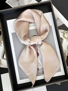 Détail d'un élégant foulard en satin champagne noué, posé sur un magazine de mode chic