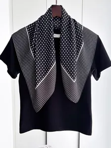 Close-up of a black and white polka dot silk scarf draped on a black t-shirt neckline