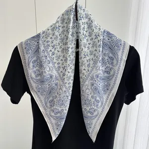 Detailed texture of paisley and floral pattern on white silk scarf against dark shirt