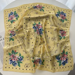 Detailed shot of yellow silk scarf featuring floral paisley patterns and polka dot border