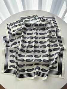 Detailed flat lay of a paisley print silk square scarf on a white table with soft lighting
