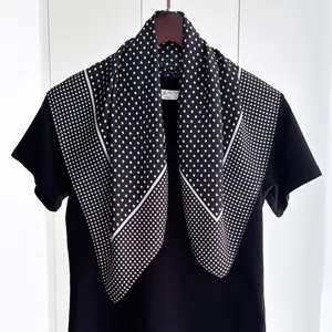 Close-up of black silk-like square scarf with white polka dots on a wooden hanger