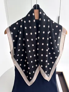 Detailed close-up of a French style black polka dot scarf hanging on a wooden hanger