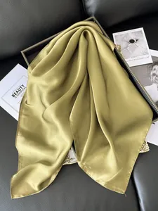 Détail d'un foulard en satin vert olive avec texture soyeuse et bords ourlés fins