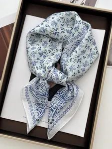 Detail view of luxurious floral silk scarf with blue paisley pattern on a white base